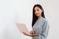 Kaboompics - Asian Woman Holding an Open Pink Laptop Against a White Background