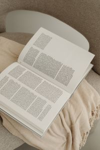 Kaboompics - Open Book on Beige Armchair with Fringed Throw, Top View