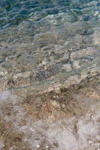 Kaboompics - Clear Shallow Seawater over Dark Pebbles with Wavy Reflections