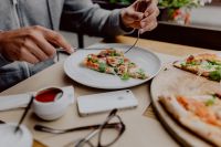 Kaboompics - Hands Sharing a Cheesy Pizza Slice in a Cozy Restaurant