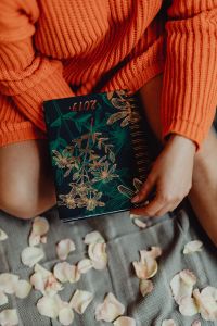 Kaboompics - A woman in an orange sweater holds the 2019 calendar in her hands