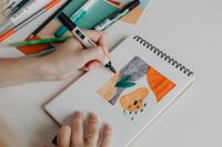 Kaboompics - Close-Up of Hand Using a Marker to Color a Sketchbook Illustration, Design Studio Flat Lay