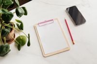 Kaboompics - Clipboard on a marble table, a mobile phone and a pencil, copy space