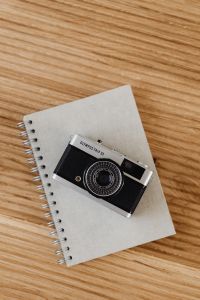 Kaboompics - Diagonal Camera Flat Lay on Spiral Notebook and Wood Grain