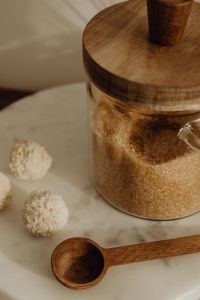 Kaboompics - Brown Sugar Grain Texture in Glass Pantry Jar with Wooden Spoon, Close-Up Food Background