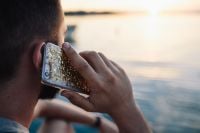 Kaboompics - Man Taking a Phone Call by the Sea with a Gold-Patterned Smartphone