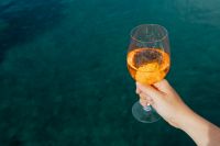 Kaboompics - Aperol Spritz Glass Held over Dark Seawater