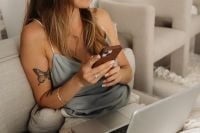 Kaboompics - Woman Checking Smartphone on a Sofa in Satin Loungewear, Cozy Work from Home Lifestyle Photography