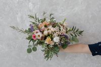 Kaboompics - Wide Mixed Flower Bouquet Held by a Person in a Navy Shirt against a Textured Wall