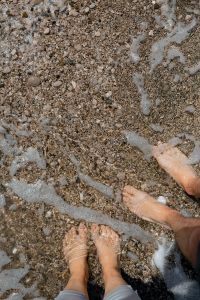 Kaboompics - Bare Feet in Clear Sea Foam on a Pebble Beach, Top-Down Coastal Photo