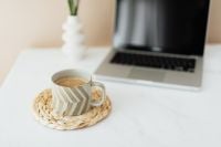 Kaboompics - Coffee on a Woven Coaster beside Laptop in Neutral Home Office