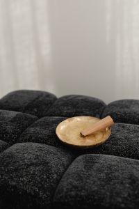 Kaboompics - Pale Wooden Stick on an Iridescent Dish over Black Tufted Upholstery with White Wall Copy Space