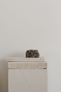 Kaboompics - Dark Stone Sculpture on a White Textured Pedestal