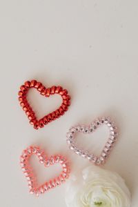 Kaboompics - Red and Pink Beaded Hearts with a White Shell on Speckled Beige Surface
