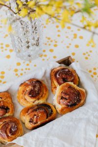 Kaboompics - Overhead Cinnamon Roll Bakery Table with Glass Vase and Yellow Blossoms