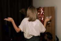 Kaboompics - Woman Holding a Champagne Glass and Blue Party Hat from Behind