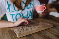 Kaboompics - Woman with wireless wooden keyboard and cup of coffee