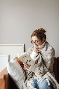 Kaboompics - Cocooning on the Sofa: Woman Reading in Glasses