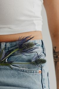 Kaboompics - White Ribbed Crop Top and High-Waisted Jeans with Purple Dried Flower Accent