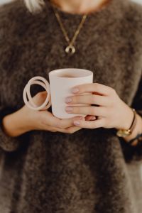 Kaboompics - Close-Up of Hands Holding a Pink Mug Against a Brown Knit Sweater