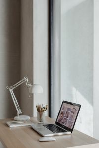 Home Office Desk Styling with Laptop, Art Supplies, Desk Lamp and Spring Daffodils by a Large Window