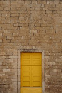 Kaboompics - Mustard Yellow Paneled Door in Weathered Stone Brick Facade