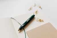 Kaboompics - Green Fountain Pen on Open Notebook with Gold Clips and Wide White Copy Space for Office Design