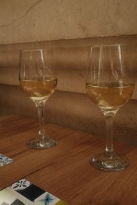 Kaboompics - Two White Wine Glasses on Rustic Wooden Table Against Stone Wall