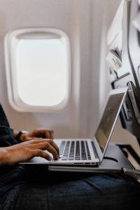 Unrecognizable man with notebook sitting inside an airplane