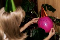Kaboompics - Woman Decorating a Pink Happy Birthday Balloon beside Greenery