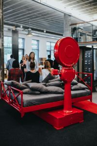 Design Exhibition Display with a Red Weighing Scale, Bed, Black-and-White Bedding and Color-Block Pillows