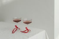 Kaboompics - Two Crystal Cocktail Glasses with Red Satin Bows on a White Table