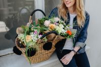 Kaboompics - Smiling Woman Holding a Wicker Basket of Colorful Flowers