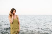 Kaboompics - Woman Talking on Her Phone by the Sea in a Green Dress, Open-Sky Beach Lifestyle Photo