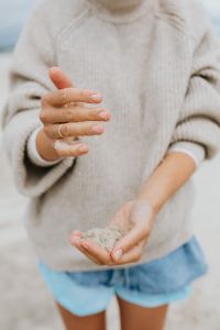 Kaboompics - Close-Up of a Woman Sifting Beach Sand Through Her Fingers in a Knit Sweater