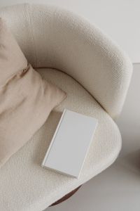 Kaboompics - Blank Hardcover Book Mockup on a Bouclé Armchair with Linen Pillow