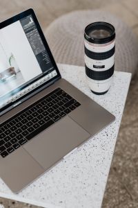 Kaboompics - White Telephoto Lens beside Laptop with Photo Editing Interface