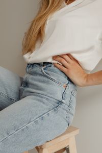 Kaboompics - Side Pose with Hand on Hip under White Button-Down Shirt, High-Waisted Denim Jeans
