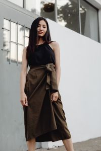 Kaboompics - Asian Woman Looking Down in Black Top and Brown Wrap Skirt at Modern Building