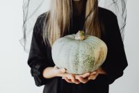 Kaboompics - Woman in Black Halloween Costume Holding a Gray Pumpkin
