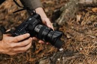 Kaboompics - Handheld Black Cinema Camera with Lens Hood on Forest Floor