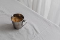 Kaboompics - Chrome Coffee Cup Close-Up on White Tablecloth