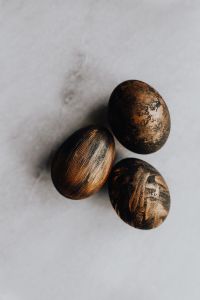 Kaboompics - Three Black and Bronze Easter Eggs on White Fabric with Copy Space