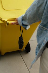 Kaboompics - Hand Opening A Yellow Recycling Bin With Disposable Camera