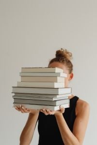 Kaboompics - Woman Holding a Tall Stack of Books with Copy Space