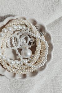 Kaboompics - White Pearl Necklace and Drop Pendant in Scalloped Bowl, Vertical Flat Lay with Copy Space