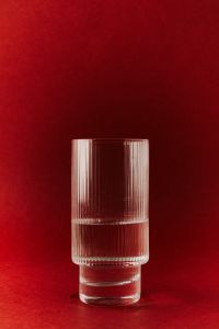 Kaboompics - Tall Ribbed Glass on Red Background