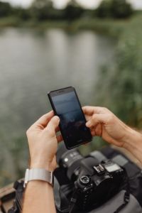Man Using Phone by Lake
