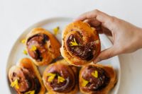 Kaboompics - Hand Lifting a Cinnamon Roll from a Plate of Pastries for Bakery Lifestyle Content