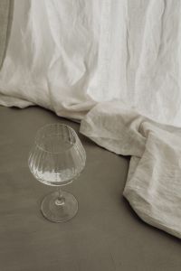 Kaboompics - Empty Ribbed Wine Glass on Greige Linen with White Drapery
